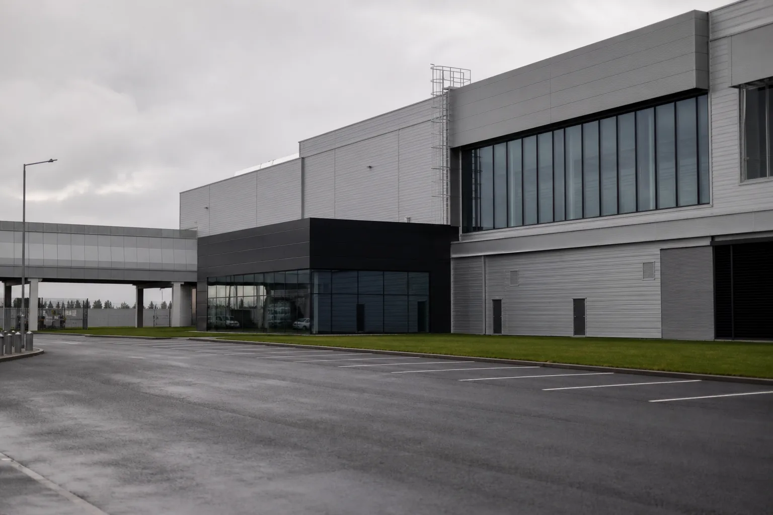 Symbolbild: Ein modernes Autowerk an einem trüben Tag steht für den wachsenden Spardruck in der Branche.