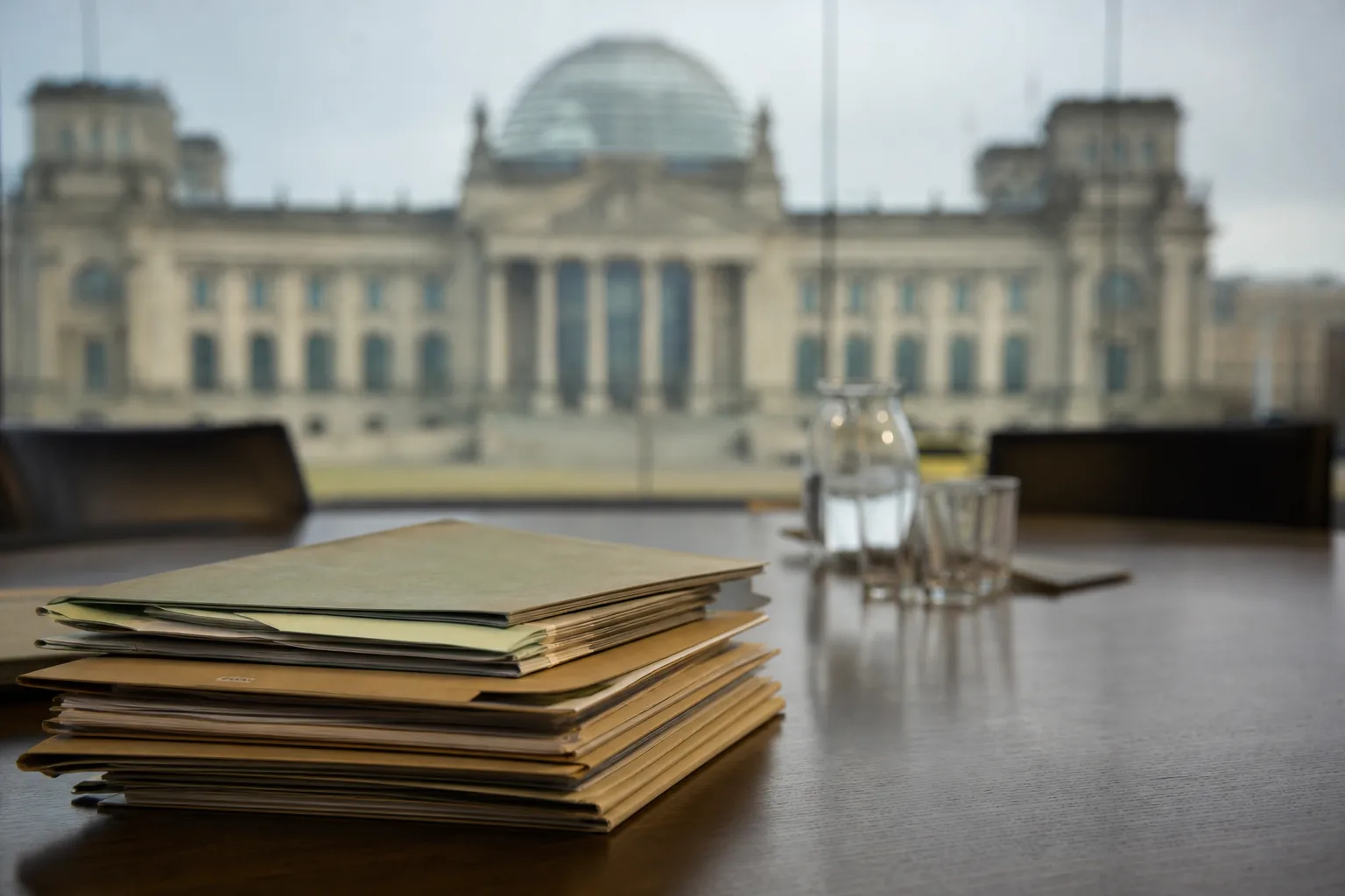 Symbolbild: Rentenunterlagen auf einem Konferenztisch vor politischer Kulisse.