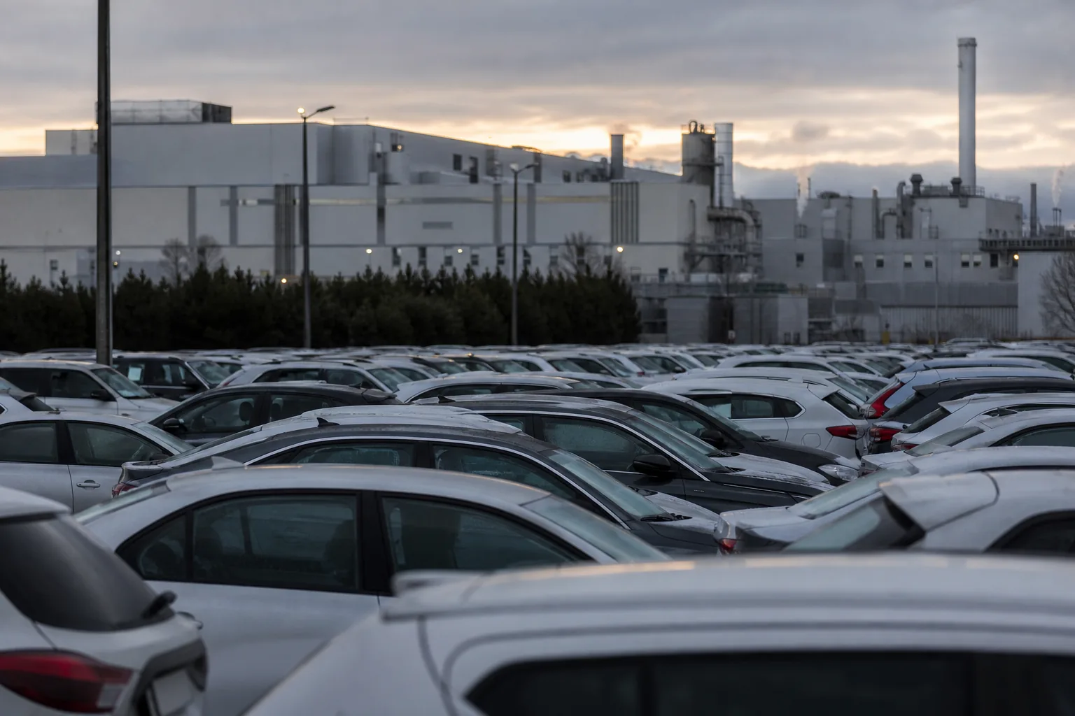 Symbolbild: Reihen von Fahrzeugen vor einem Werk stehen für den wachsenden Druck auf die Autoindustrie.